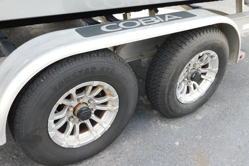 Slide: The Image of Trailer wheels of a 2021 Cobia 262 Center Console boat on pavement. - 52