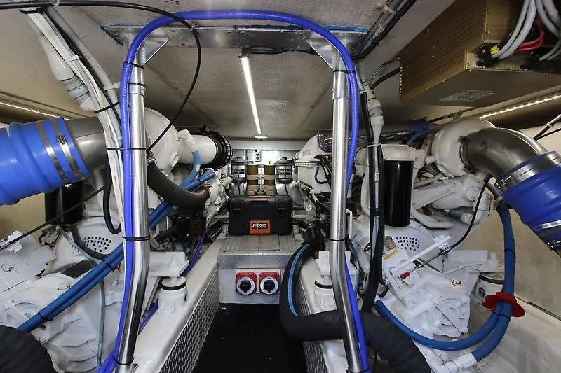 Slide: The Image of Engine room of a 2002 Ocean Yachts model, featuring complex machinery and blue hoses. - 22