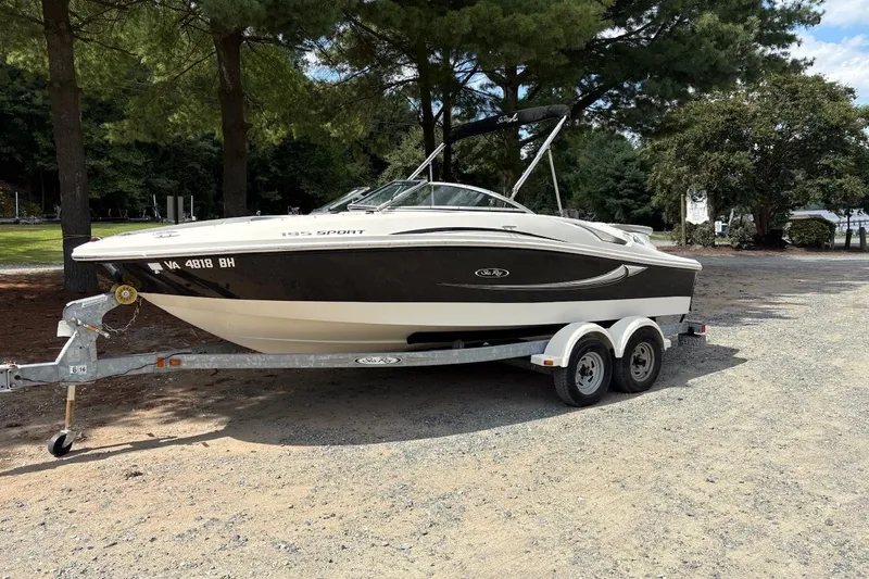 The Image of 2008 Sea Ray 195 Sport boat on trailer, parked outdoors under trees. - 0