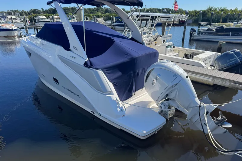 Slide: The Image of 2024 Regal 26 XO boat docked with blue cover and Yamaha outboard motor. - 2