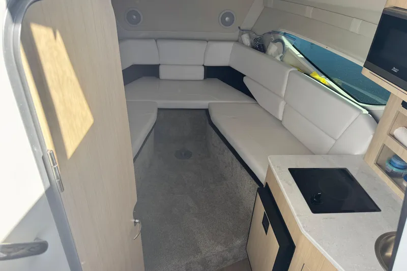 Slide: The Image of 2024 Regal 26 XO boat interior with white seating, kitchenette, and modern design. - 20