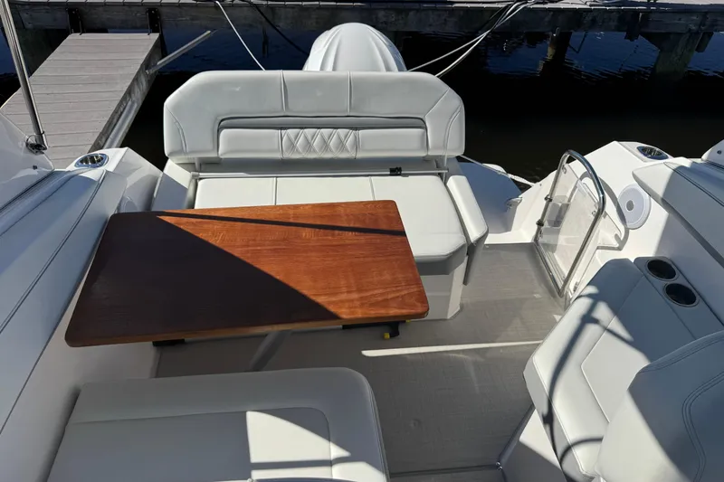 Slide: The Image of 2024 Regal 26 XO boat interior with seating and wooden table, dockside view. - 8
