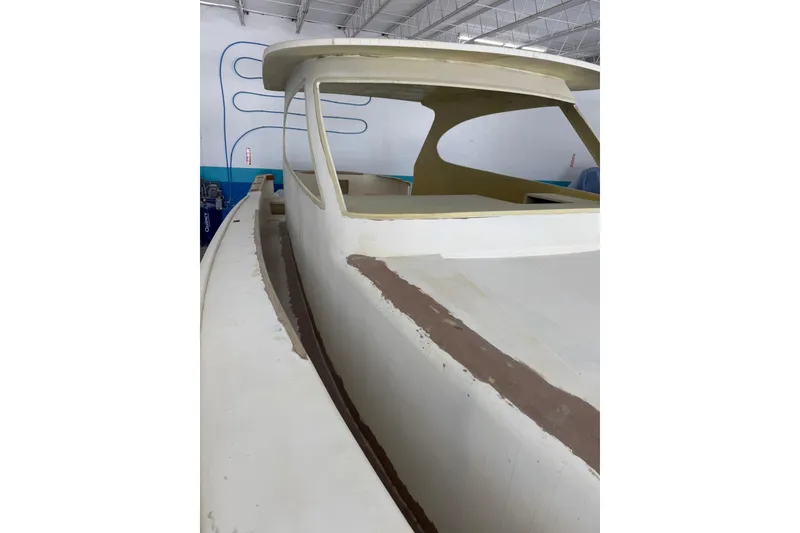 Slide: The Image of 2025 Xcelerator Walk Around boat under construction in a spacious indoor facility. - 2