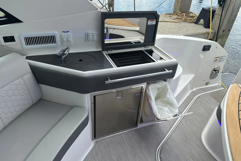 Slide: The Image of 2021 Sea Ray Sundancer 320 Coupe Outboard boat interior with grill and seating area. - 14