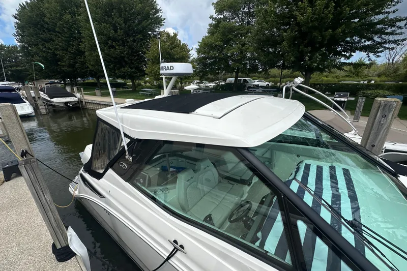 Slide: The Image of 2021 Sea Ray Sundancer 320 Coupe Outboard docked at marina, surrounded by trees. - 6