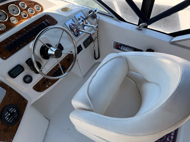 Slide: The Image of 2002 Bayliner 3488 Motoryacht helm with steering wheel, controls, and white captain's chair. - 12