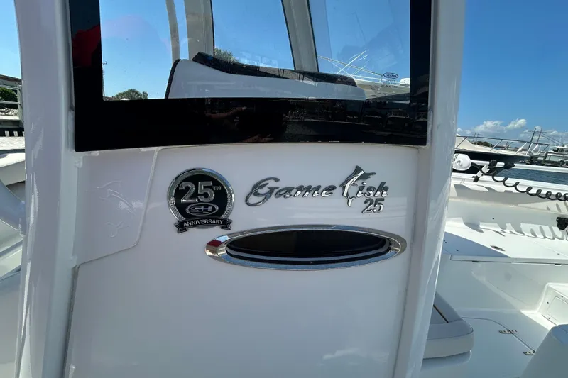 Slide: The Image of 2021 Sea Hunt Gamefish 25 boat with 25th anniversary emblem, docked under clear skies. - 34