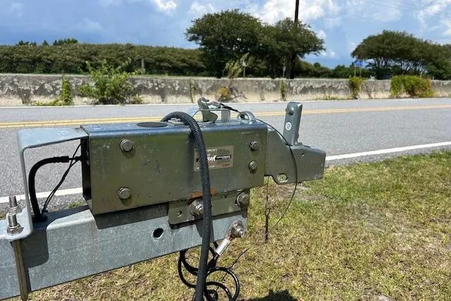 Slide: The Image of Trailer hitch mechanism for 2021 Sea Hunt Gamefish 25 on roadside, with trees and sky background. - 41
