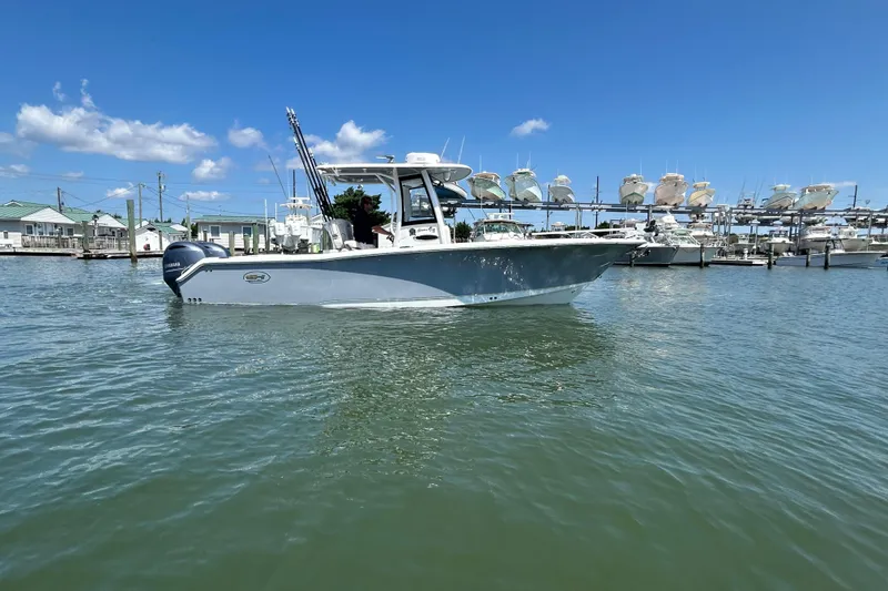 Slide: The Image of 2021 Sea Hunt Gamefish 25 boat on water, marina background, clear sky. - 9
