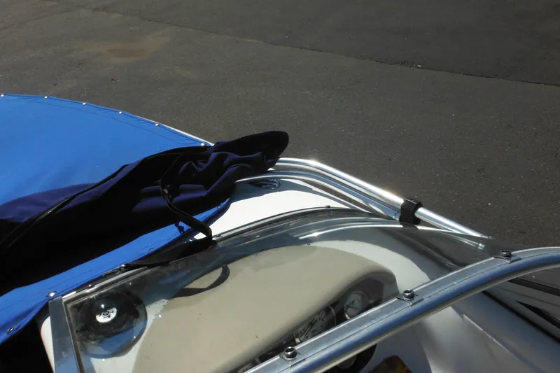 Slide: The Image of 2003 Chaparral 180 SS boat with blue cover and windshield, parked on asphalt. - 22