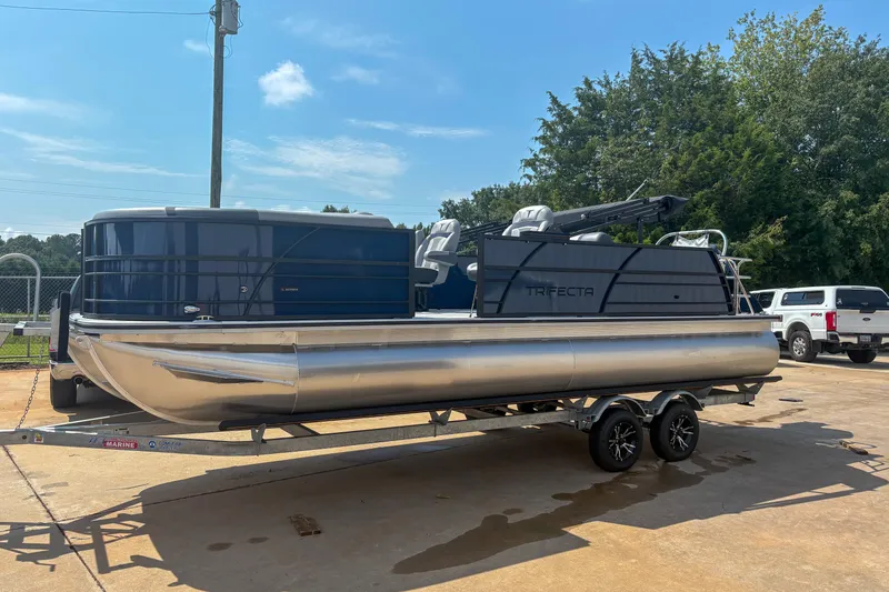 The Image of 2025 Trifecta 24 UL CS pontoon boat on trailer, parked outdoors. - 1