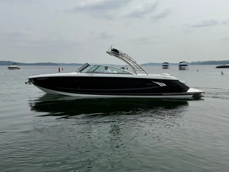 Slide: The Image of 2016 Cobalt A28 boat cruising on a calm lake with other boats in the background. - 11