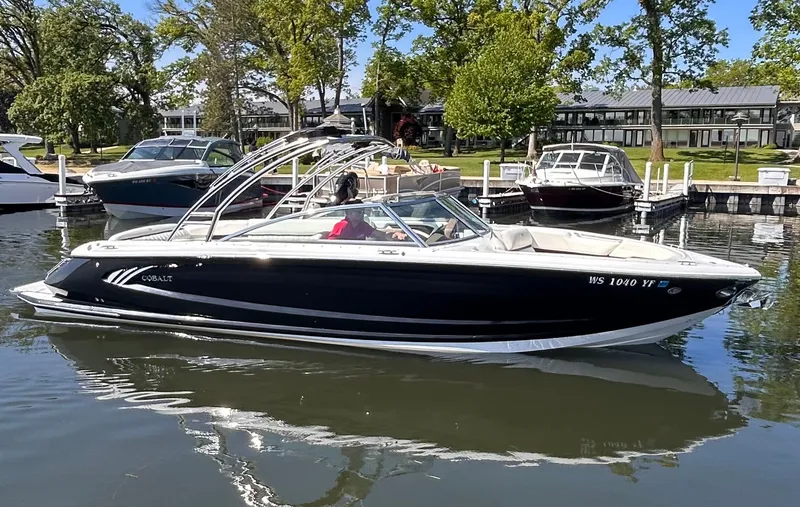 Slide: The Image of 2016 Cobalt A28 boat docked on a calm lake with trees in the background. - 2