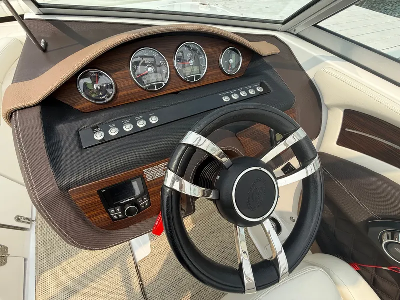 Slide: The Image of 2016 Cobalt A28 boat dashboard with wood accents and modern steering wheel design. - 20