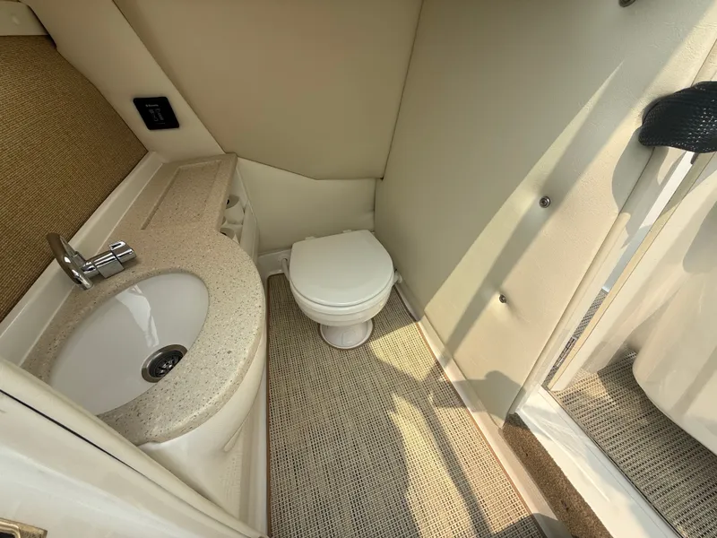 Slide: The Image of 2016 Cobalt A28 boat bathroom with sink and toilet, featuring beige interior design. - 22
