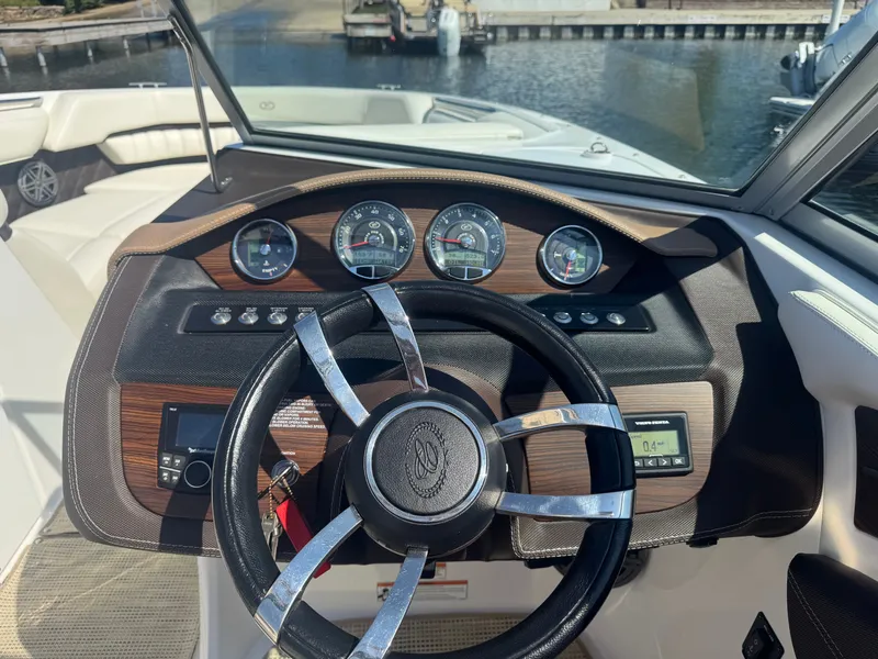 Slide: The Image of Steering wheel and dashboard of a 2016 Cobalt A28 boat, featuring gauges and controls. - 9