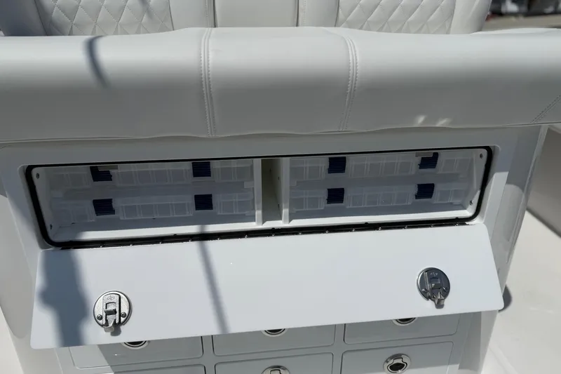 Slide: The Image of 2026 Regulator 31 boat storage compartment with white cushioned seating and secure latches. - 48