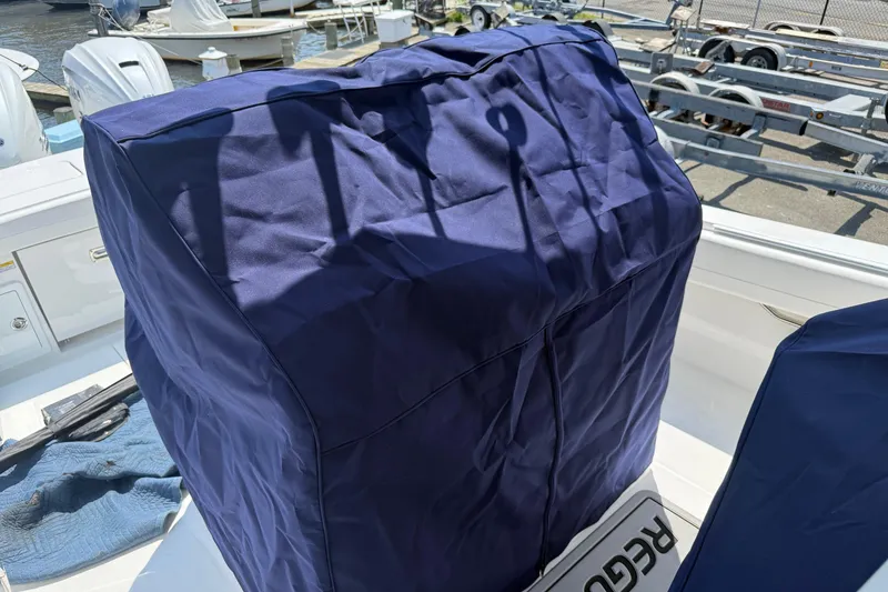 Slide: The Image of 2026 Regulator 31 boat with blue cover, docked near trailers. - 56