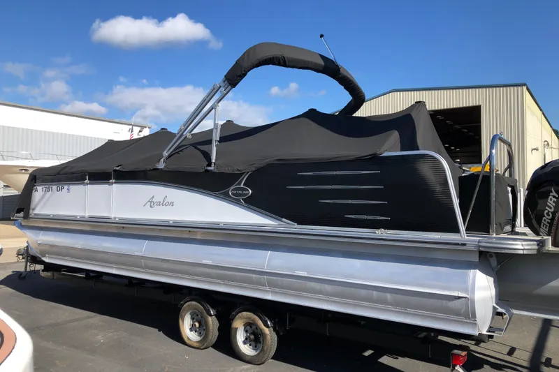 Slide: The Image of 2015 Avalon Catalina Entertainer 25' pontoon boat on trailer, covered and parked outdoors. - 2