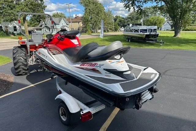 Slide: The Image of 2012 Kawasaki Ultra LX jet ski on trailer, parked on driveway with tractor nearby. - 2