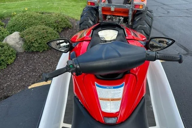 Slide: The Image of Red 2012 Kawasaki Ultra LX jet ski on trailer, parked near green shrubs and a tractor. - 8