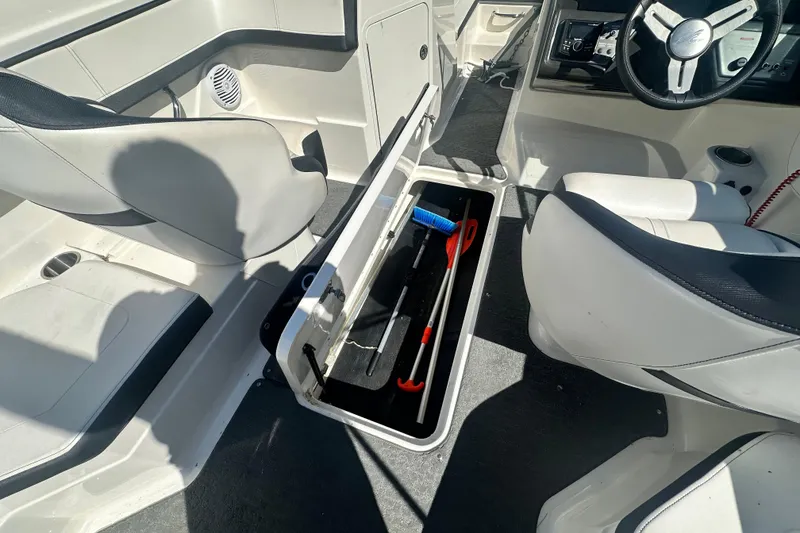 Slide: The Image of 2018 Sea Ray SPX 210 boat interior with open storage compartment and steering wheel. - 21