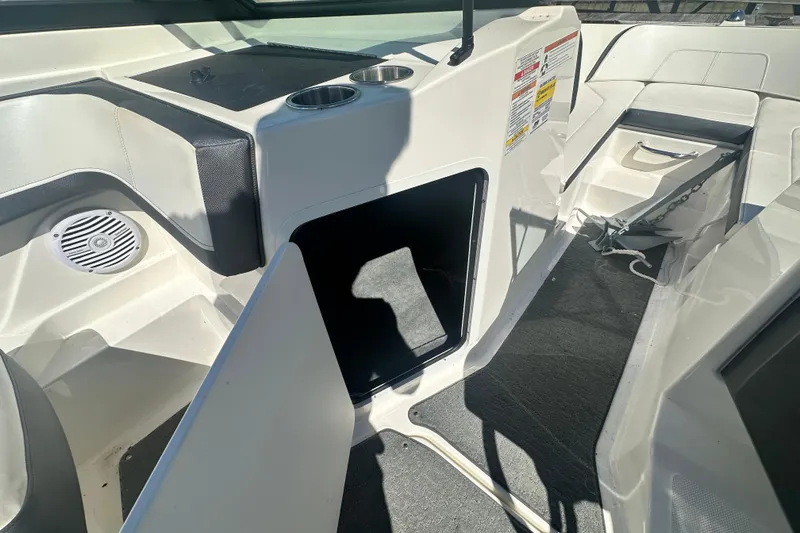 Slide: The Image of 2018 Sea Ray SPX 210 boat interior with open storage compartment and cup holders. - 22