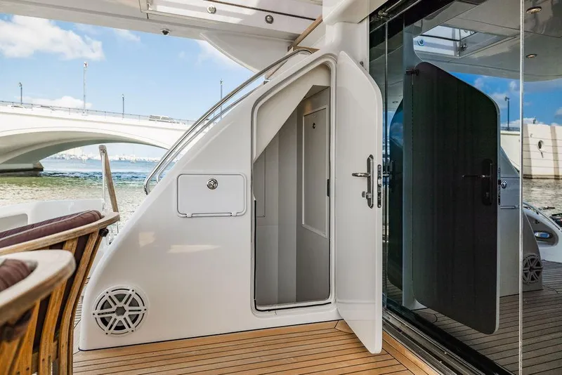 Slide: The Image of 2013 Hatteras 80 Motor Yacht deck with open door, wooden flooring, and scenic bridge view. - 22