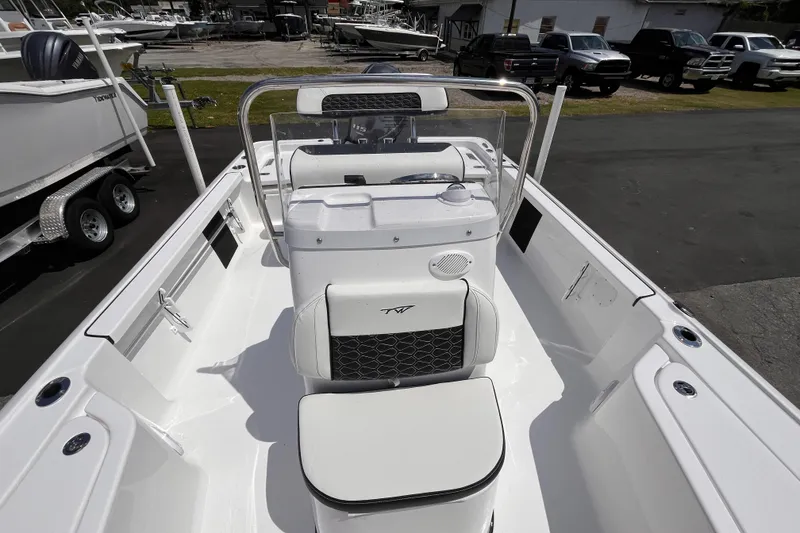 Slide: The Image of 2026 Tidewater 1910 Bay Max boat interior with seating and console, parked outdoors. - 10