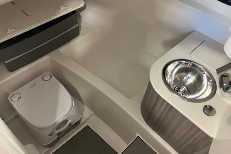 Slide: The Image of 2025 Sea Ray SDX 270 boat interior with compact sink and portable toilet. - 12