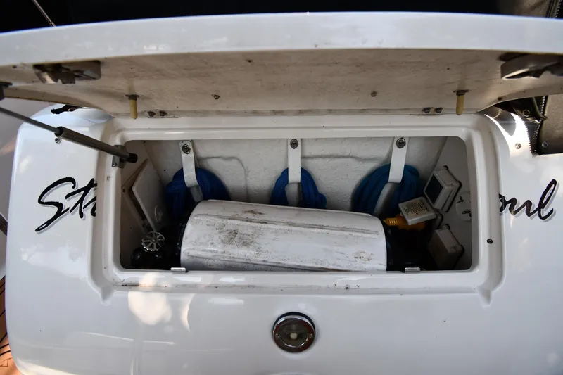 Slide: The Image of Open storage compartment on a 2005 Sea Ray 300 Sundancer boat, showing equipment and ropes. - 23