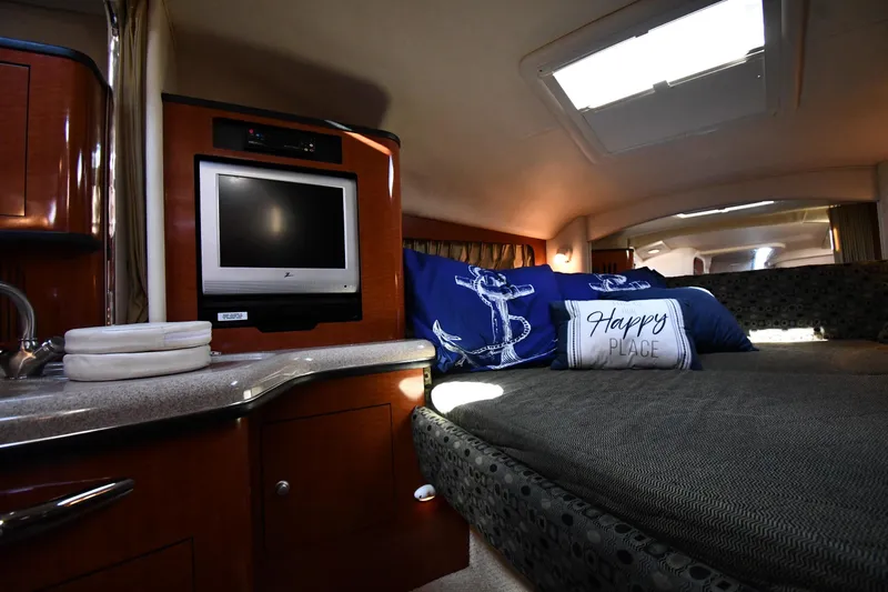 Slide: The Image of 2005 Sea Ray 300 Sundancer cabin interior with TV, cozy bed, and nautical decor. - 27