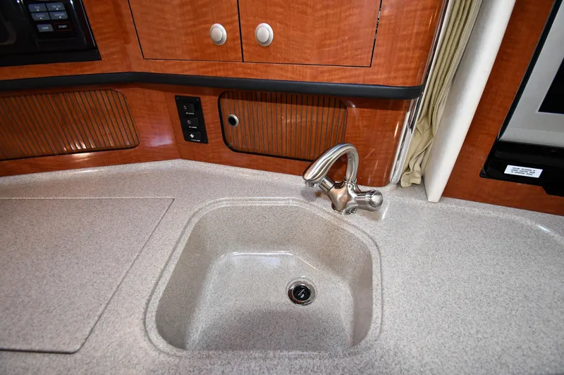 Slide: The Image of 2005 Sea Ray 300 Sundancer kitchen sink with modern faucet and wood cabinetry. - 35