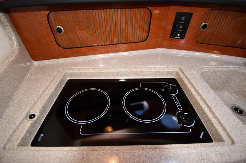 Slide: The Image of 2005 Sea Ray 300 Sundancer kitchen with electric stovetop and wooden cabinetry. - 36