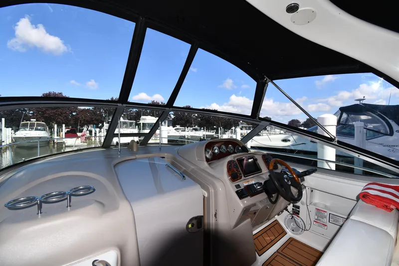 Slide: The Image of Interior view of 2005 Sea Ray 300 Sundancer boat at marina, featuring helm and dashboard. - 9