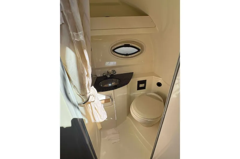 Slide: The Image of 2013 Monterey 260 SCR Sport Cruiser bathroom with sink, toilet, and porthole window. - 11