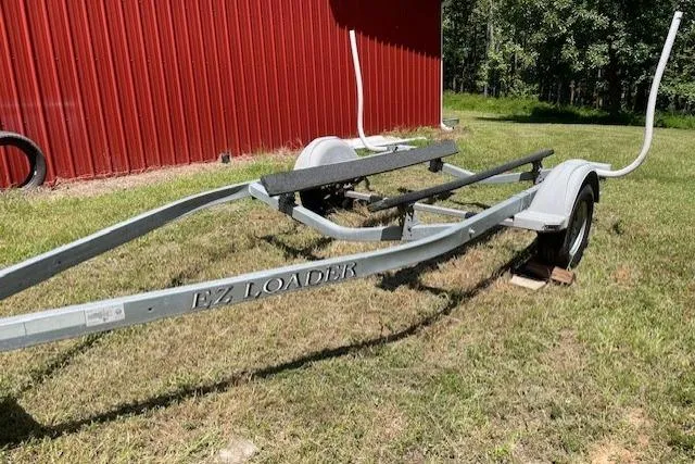 Slide: The Image of Trailer for 2009 Pro-Line Pro Lite 20 CC boat, parked on grass near red building. - 12