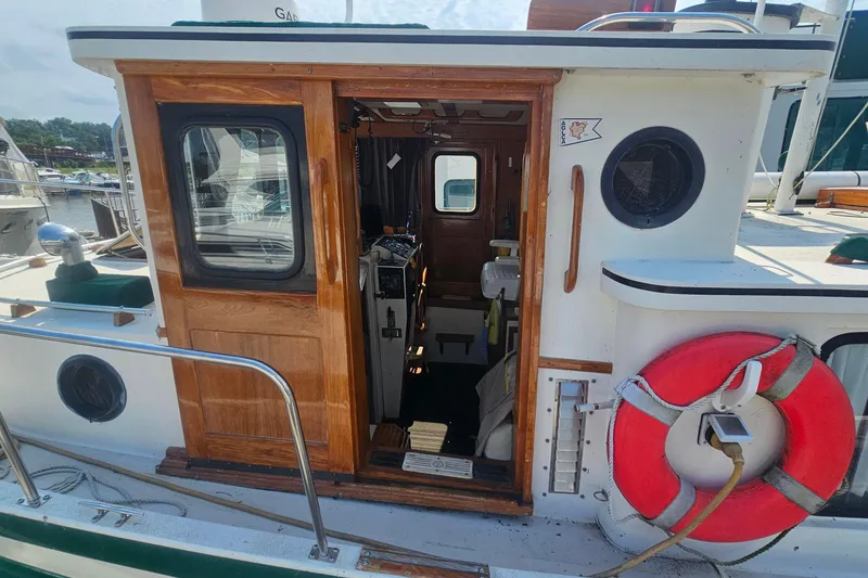 Slide: The Image of 1982 Nordic Tug 26 boat with wooden door, life preserver, and interior view at marina. - 11
