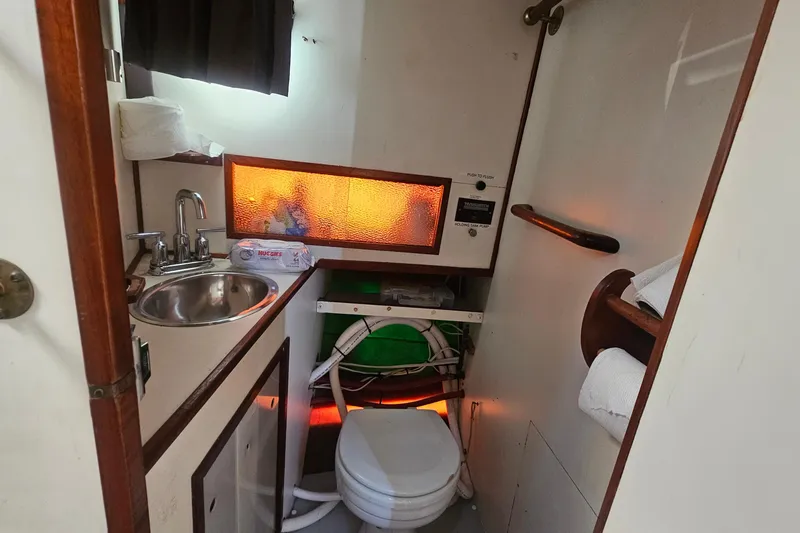 Slide: The Image of 1982 Nordic Tug 26 bathroom with sink, toilet, and storage shelves. - 16