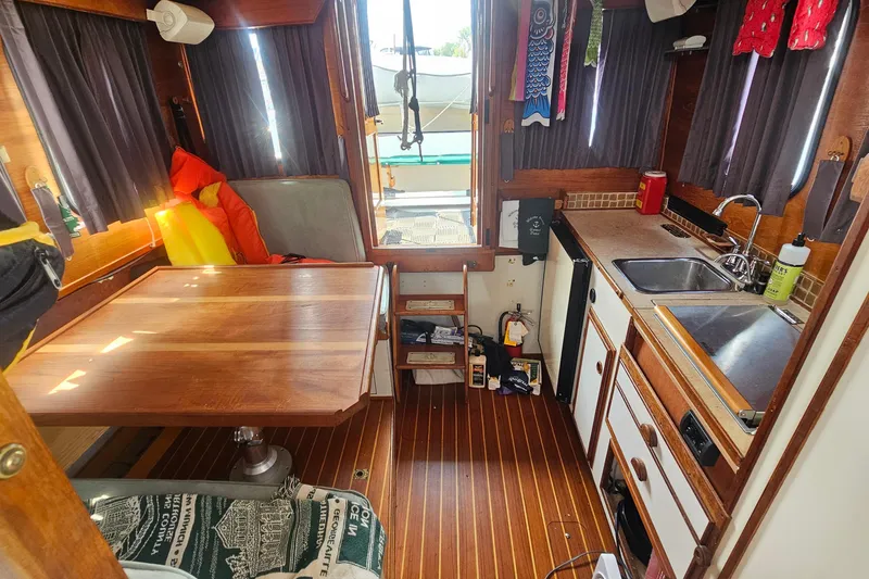 Slide: The Image of Interior of 1982 Nordic Tug 26 with wooden table, kitchenette, and cozy seating area. - 19