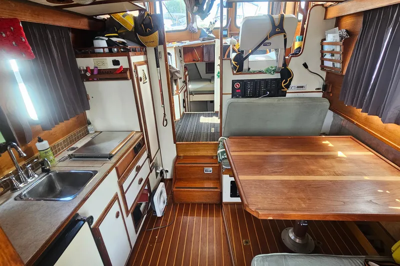 Slide: The Image of Interior of 1982 Nordic Tug 26, featuring a compact kitchen and dining area with wood accents. - 24