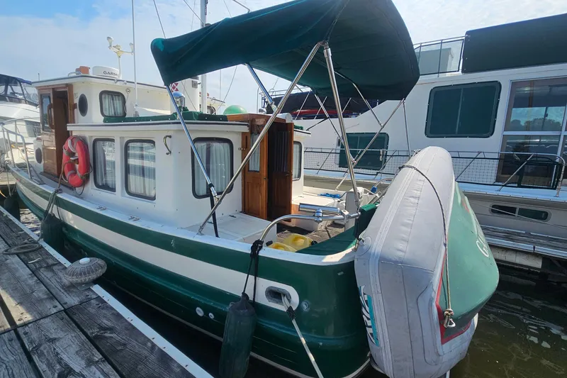 Slide: The Image of 1982 Nordic Tug 26 docked, featuring green and white exterior with canopy and lifebuoy. - 3
