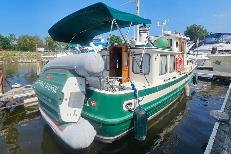 Slide: The Image of 1982 Nordic Tug 26 docked with inflatable boat, green and white exterior. - 4