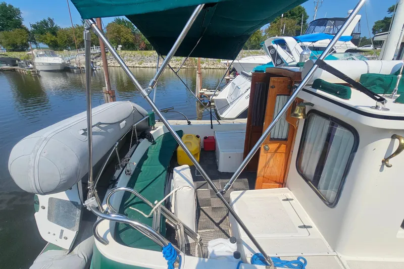 Slide: The Image of 1982 Nordic Tug 26 docked, featuring a covered deck and inflatable dinghy. - 5