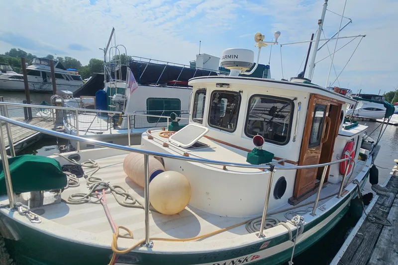 Slide: The Image of 1982 Nordic Tug 26 docked at a marina, featuring a classic design and nautical equipment. - 8
