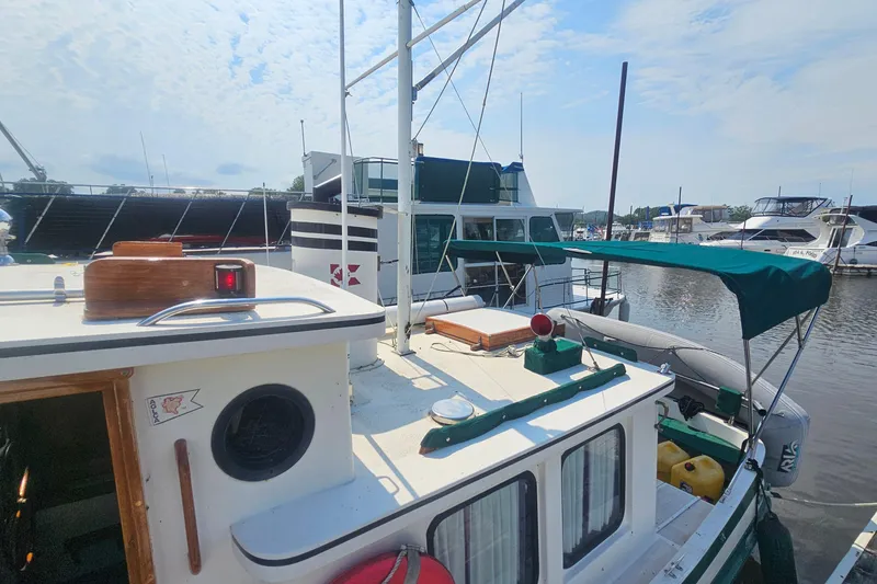 Slide: The Image of 1982 Nordic Tug 26 docked at marina, featuring green canopy and classic design. - 9