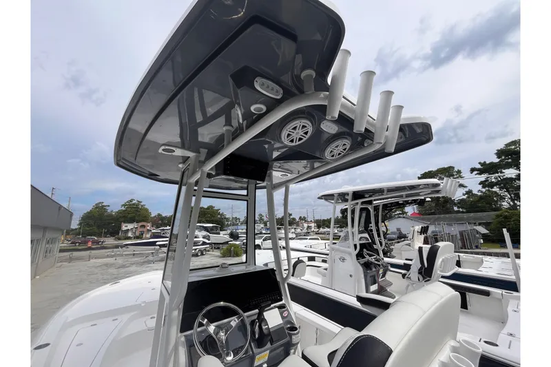 Slide: The Image of 2026 Tidewater 2210 Carolina Bay boat with T-top and rod holders, docked outdoors. - 14