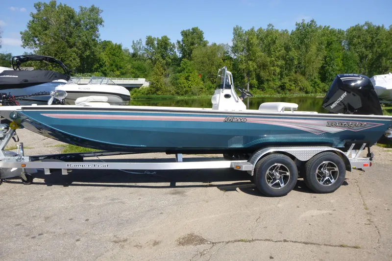 Slide: The Image of 2025 Ranger RB210 boat on trailer, parked near a lake with trees in the background. - 1