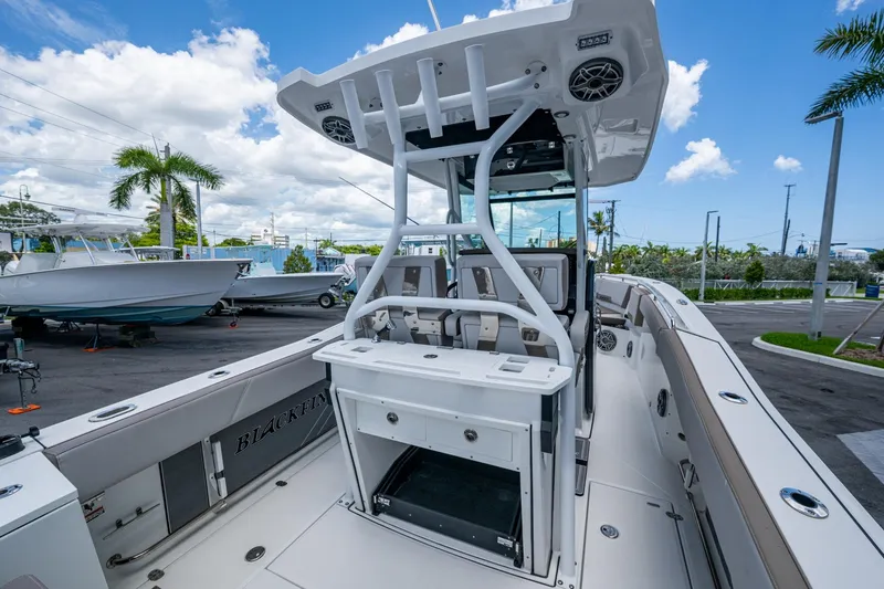 Slide: The Image of 2019 Blackfin 272 CC boat interior with seating and storage, parked outdoors under a blue sky. - 11