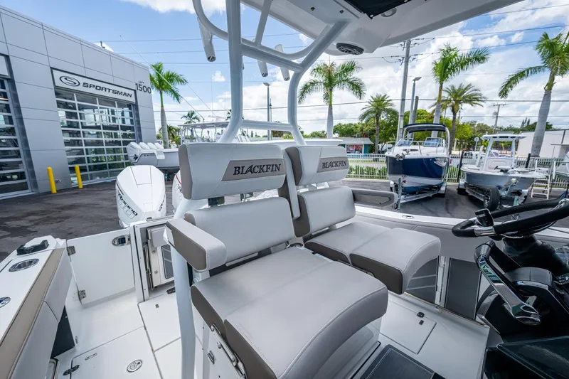 Slide: The Image of 2019 Blackfin 272 CC boat interior with seating, steering wheel, and outdoor dealership view. - 19